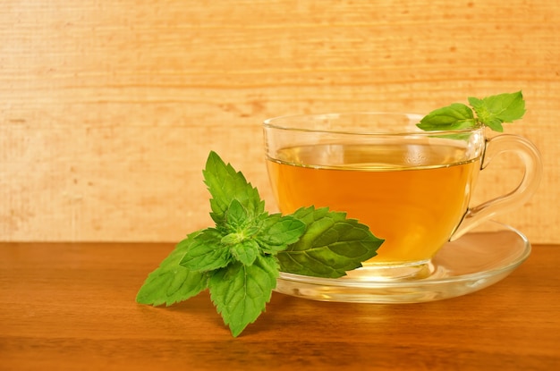 Herbal tea in a glass cup with mint on a table on the background of wooden boards