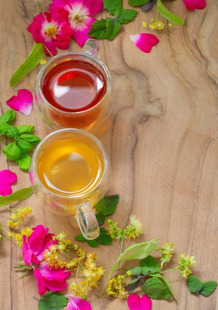 Herbal tea in glass cups with flowers and herbs on wooden background