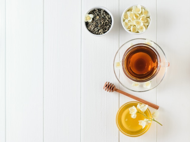 Photo herbal tea with jasmine and a bowl of flowers and honey on a table. the composition of the morning breakfast. flat lay.