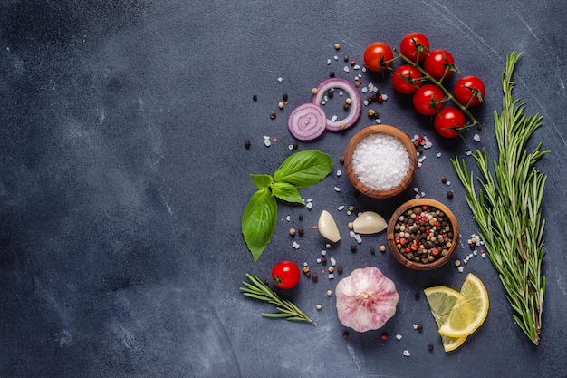 Herbs and condiments on black stone background. Top view with copy space.