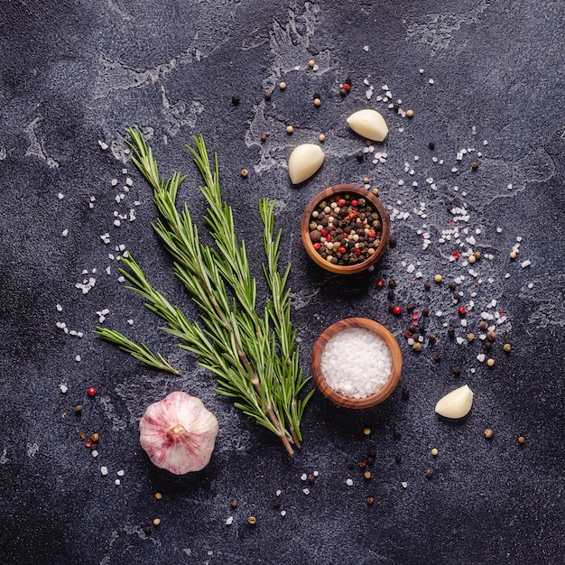 Herbs and condiments on black stone background