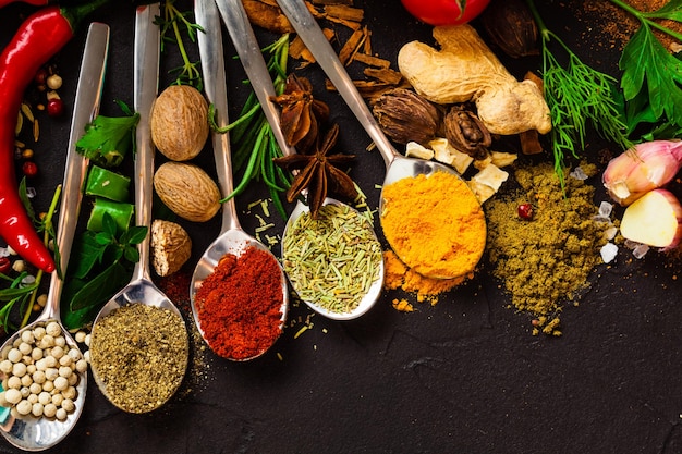 Herbs and spices over black stone background. Colorful herbs and spices for cooking.