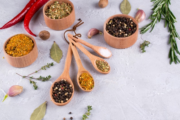 Herbs and spices  selection in wooden spoons - rosemary, garlic, salt, pepper on gray table. Food flat lay. Food cooking background