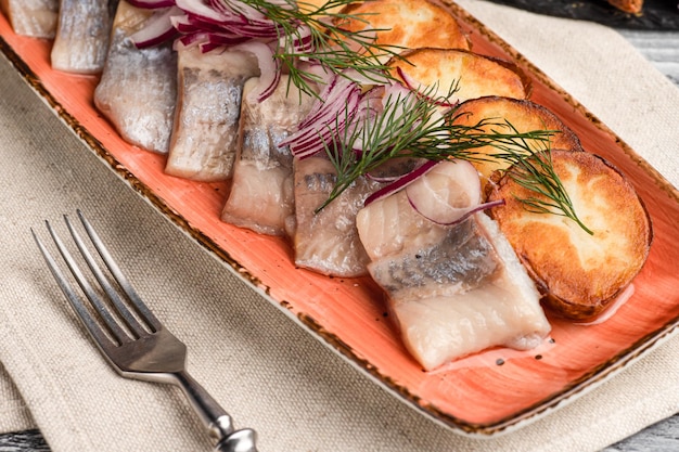 Herring with potatoes appetizer fish on a wooden white background