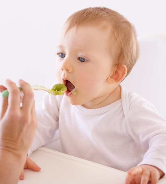 Hes got a good appetite. A cute baby accepting a spoonful of food by his mom.