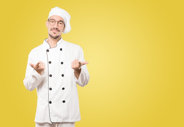 Hesitant young chef pointing at you with his finger