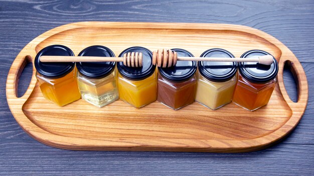 Hexagonal jars with different types and colors of fresh flower honey and a honey spoon. vitamin food for health and life