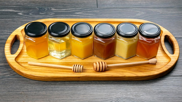 Hexagonal jars with different types and colors of fresh flower honey and a honey spoon. vitamin food for health and life