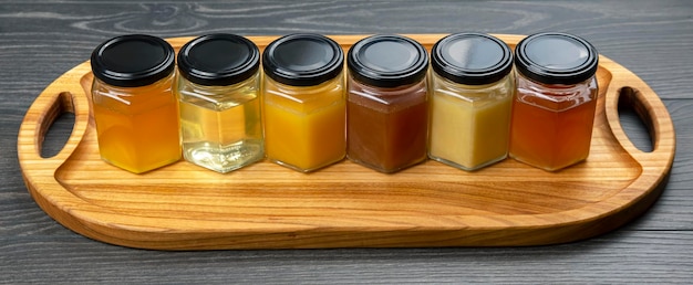 Hexagonal jars with different types and colors of fresh flower honey and a honey spoon. vitamin food for health and life