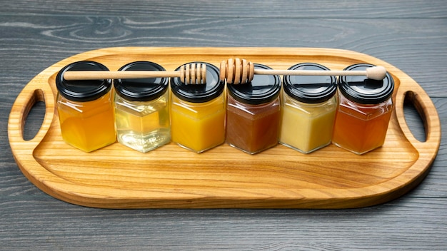 Hexagonal jars with different types and colors of fresh flower honey and a honey spoon vitamin food for health and life