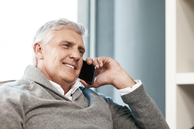 Hey Its been a while Cropped shot of a handsome mature man making a phonecall while relaxing on the sofa at home