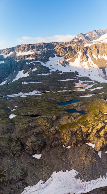 High altitude alpine landscape with majestic rocky mountain peaks. Aerial panorama at sunrise. Alps, Andes, Himalaya concept