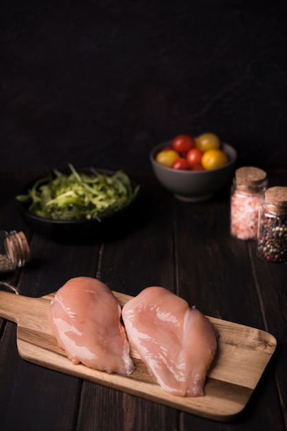 High angle chicken breast on wooden board with ingredients