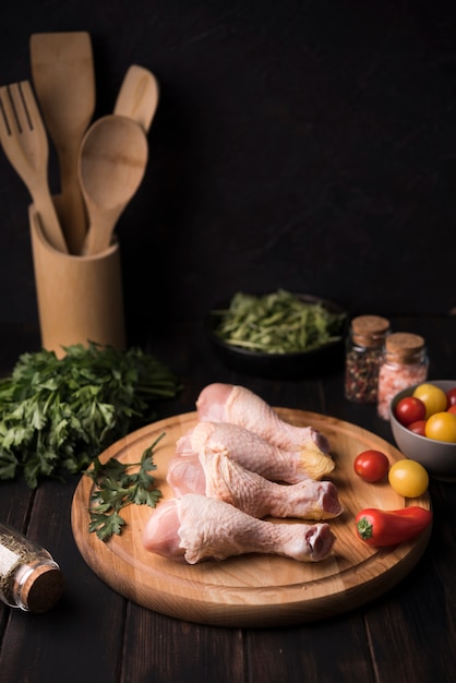 High angle chicken drumsticks on wooden board with ingredients