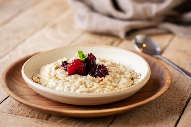 High angle close up of bowl of porridge with mixed berry compote in a cafe