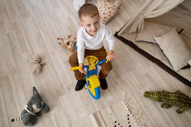 High angle cute kid on tricycle indoors