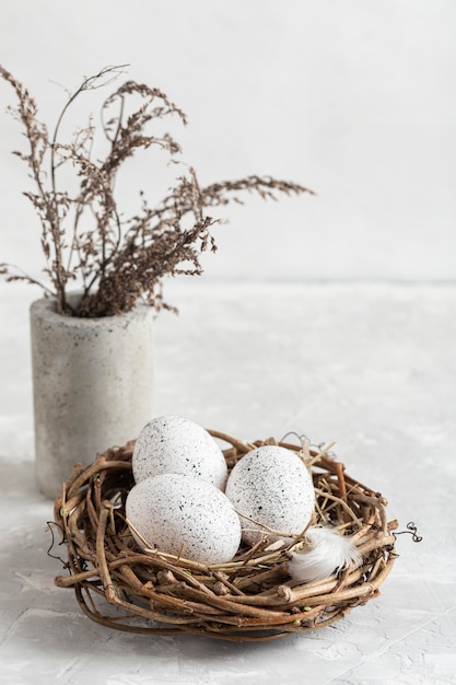 High angle of eggs for easter in nest with flowers in vase