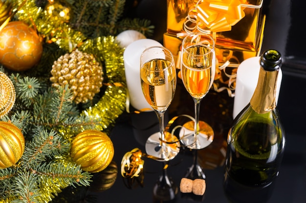 High Angle Festive Still Life - Two Glasses of Sparkling Champagne with Bottle, Candles, Gifts and Christmas Decorations on Black Background