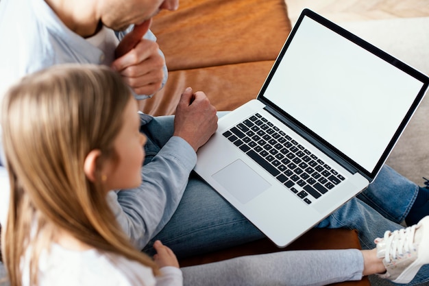 High angle of little girl and her father spend time on laptop