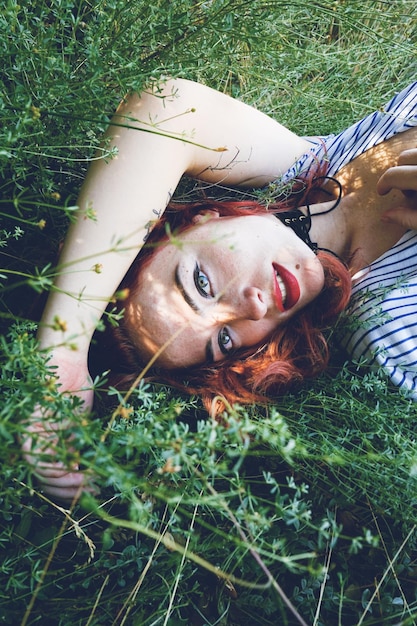 High angle portrait of young woman lying on grassy field