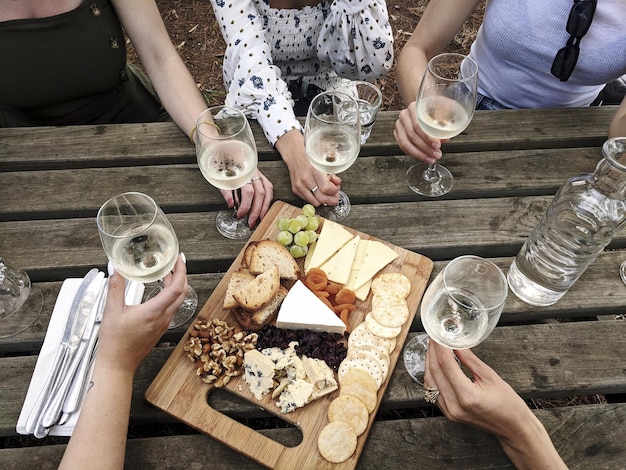 High angle shot of friends drinking wine and eating a charcuterie board