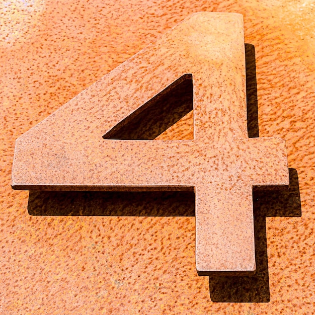 High angle shot of the number "4" on an orange stone surface