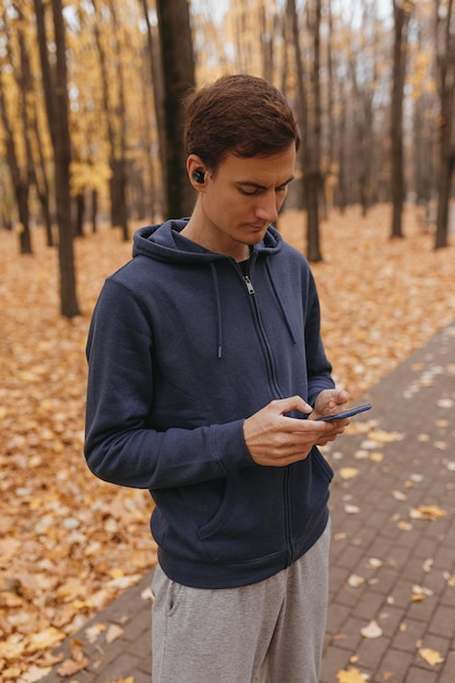 High angle of sportsman in earphones using smartphone and listening to music