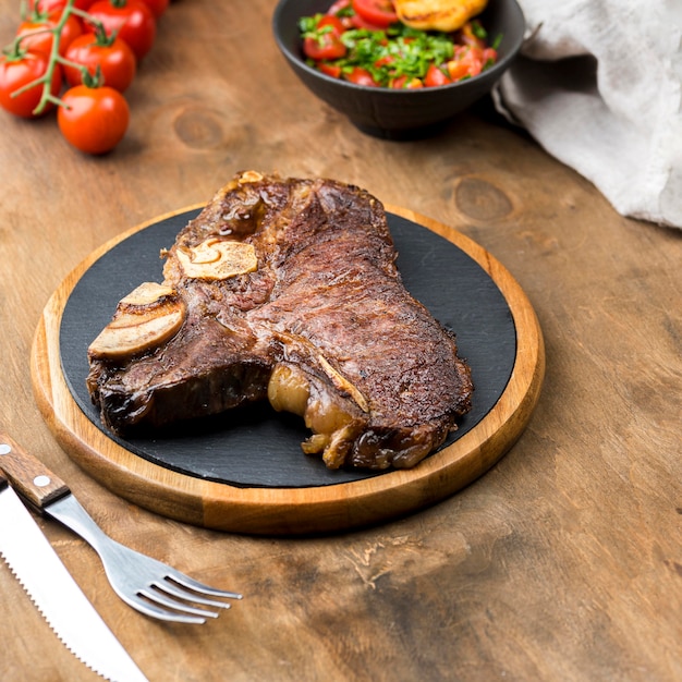 High angle of steak with cutlery and tomatoes