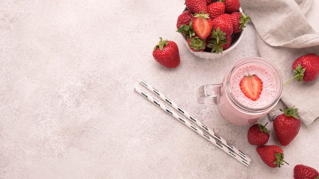 High angle of strawberry milkshake with copy space and straws