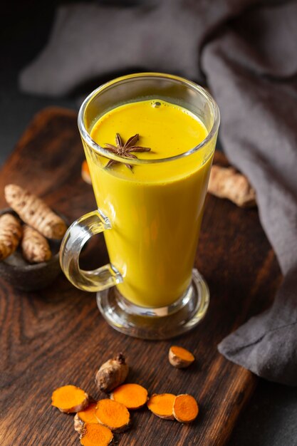 High angle tall glass with yellow drink and star anise