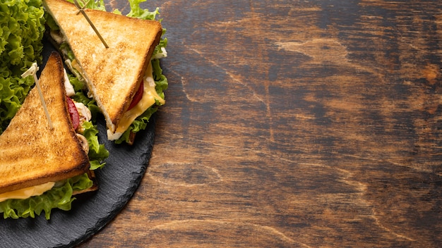 High angle of tomatoes and salad triangle sandwiches on slate with copy space