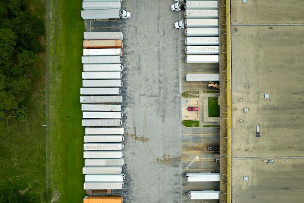 High angle view of big commercial shipping center with many freight trucks unloading and uploading goods for further distribution Global economy concept