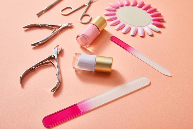 High angle view of bottles and samples of nail polish with manicure instruments on coral