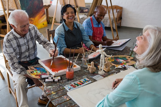 High angle view of cheerful senior friends painting on canvas