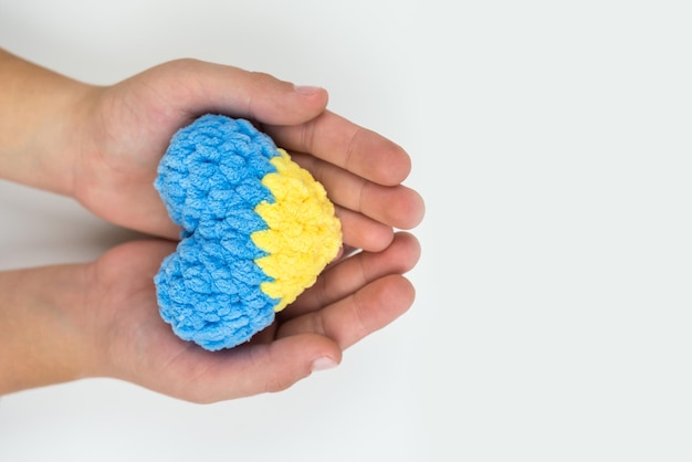 High angle view of children's hands holding a heart painted in the Ukrainian flag hearts in hands on a white background Patriotic concept I love Ukraine