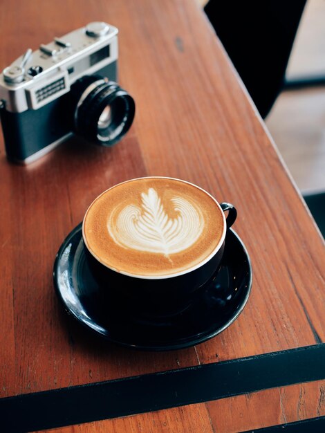 Photo high angle view of coffee cup with camera on wooden table in cafe