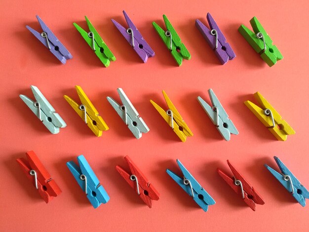 High angle view of colorful wooden clothespins arranged on coral background