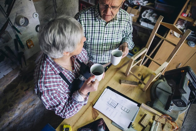 Photo high angle view of coworkers talking while having coffee in workshop