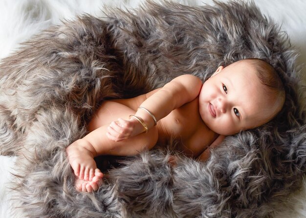 Photo high angle view of cute baby girl lying over fur blanket on bed at home