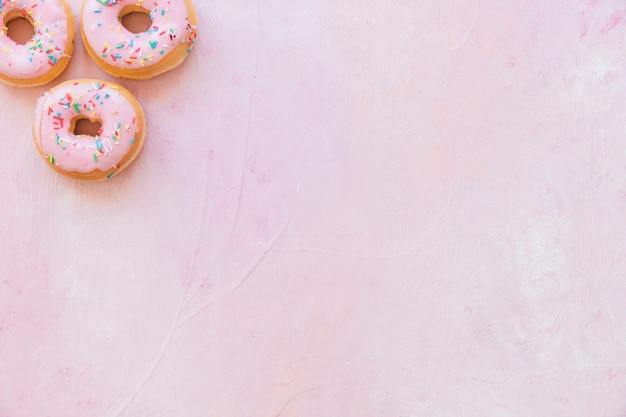 High angle view of fresh donuts with sprinkles on pink background