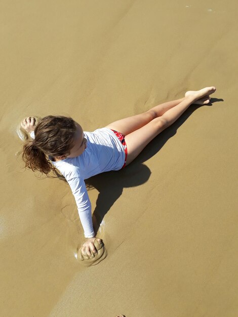 Photo high angle view of girl sitting on sand at beach