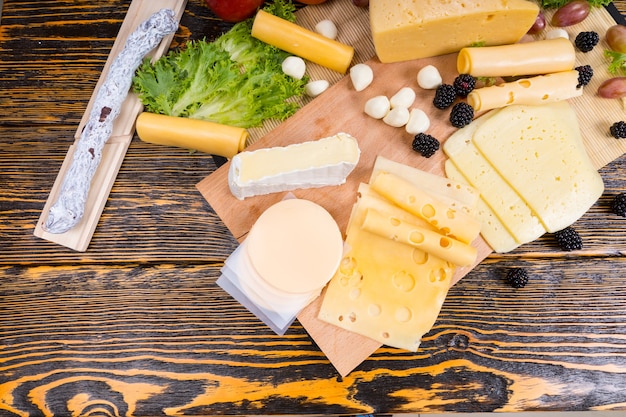 High Angle View of Gourmet Cheese Board Featuring Variety of Cheeses, Cured Meats and Fresh Fruit Served on Rustic Wooden Table with Wood Grain and Copy Space