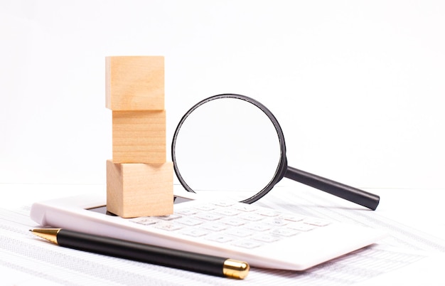 High angle view of magnifying glass with business chart calculator magnifying glass pen and wooden cubes with place to insert text