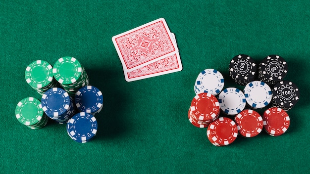 High angle view of playing cards and chips on green poker table