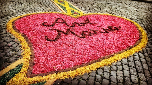 Photo high angle view of red heart shape made by petals on footpath