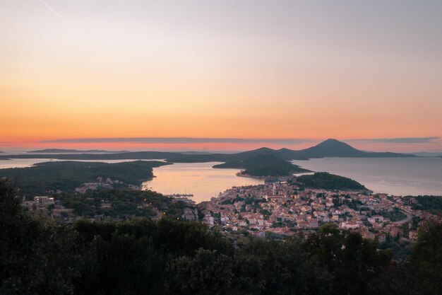 High angle view of sea and cityscape against sky during sunset