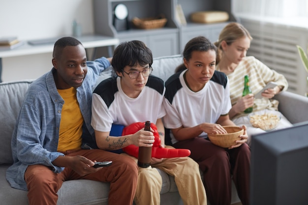 High angle view at tense group of sports fans watching game match at home and drinking beer