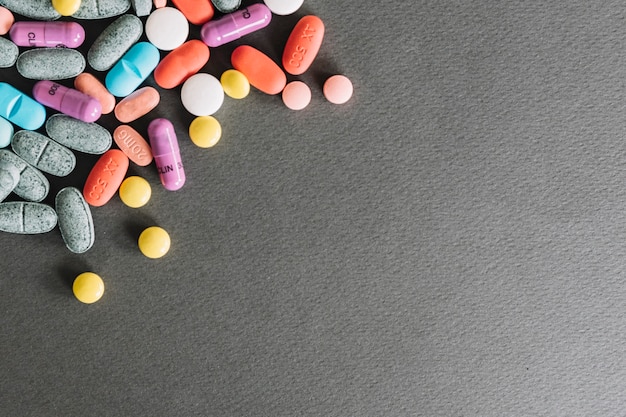 High angle view of various colorful pills on grey background