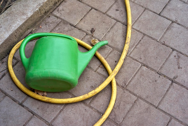 Photo high angle view of watering can and hose on footpath