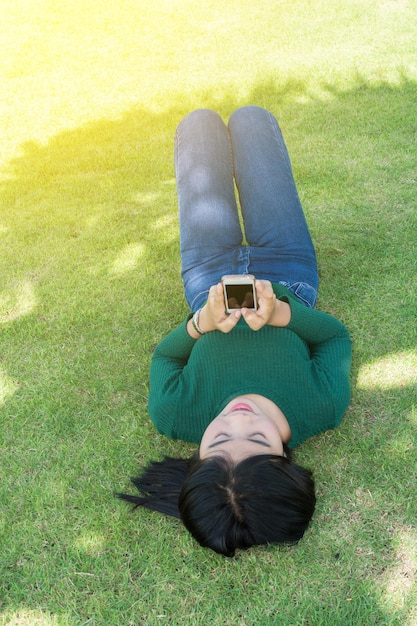 Photo high angle view of young woman using mobile phone while lying on grassy field